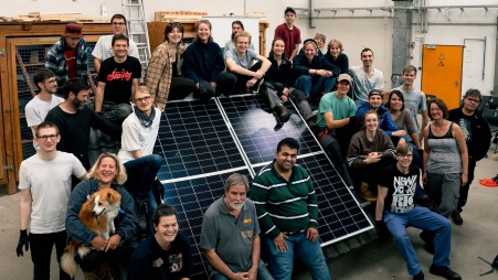 Jüngere Menschen vor und hinter einem Modell-Solardach
