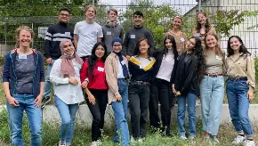 Eine Gruppe junger Menschen hat sich am Rande eines Sportplatzes zum Foto aufgestellt.