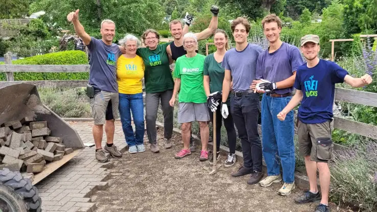 Eine sommerlich gekleidete Gruppe, manche von ihnen tragen ein Shirt mit «Freiblocks»-Aufdruck stehen Arm in Arm, lächeln und recken die Arme.