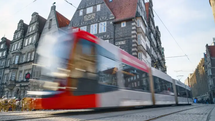 Eine Straßenbahn ist unscharf unterwegs in einer Stadt.