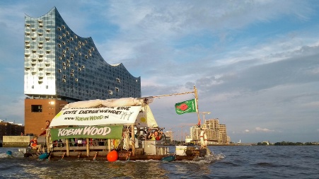 Vor der Elbphilharmonie in Hamburg fährt ein mit Flaggen und Textbannern versehenes Floß der Umweltorganisation «Robin Wood» vorbei. 