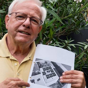 Portrait Gottfried Busch; er zeigt auf einen Plan seiner Solaranlage.